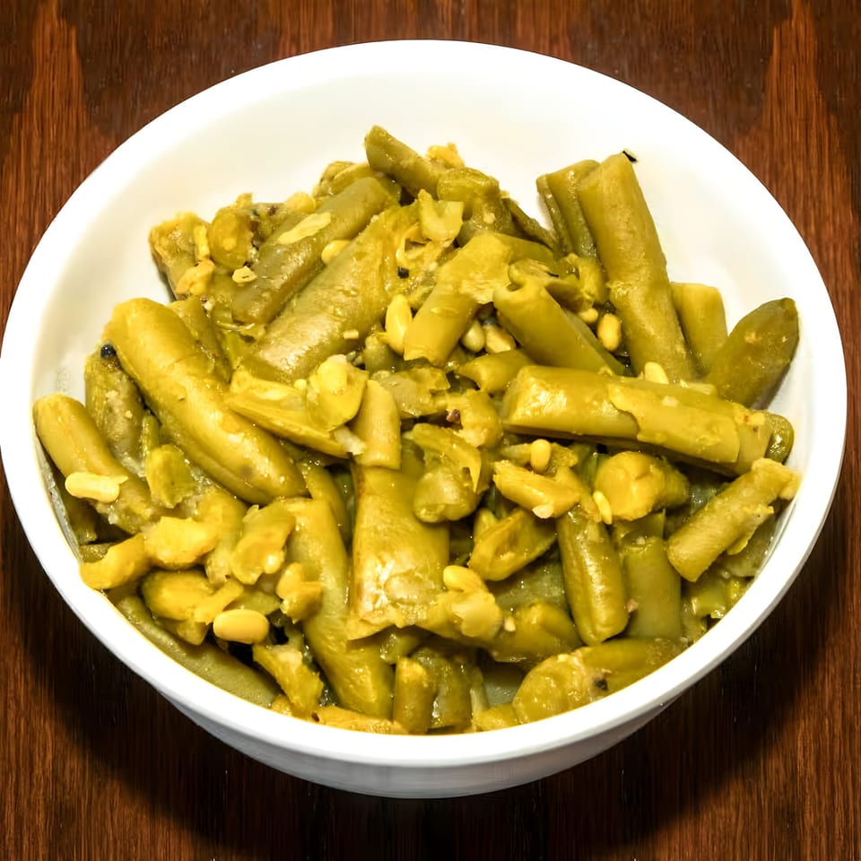 A white bowl filled with green beans and small yellow beans on a dark wooden surface.