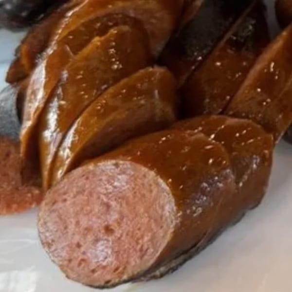 Close-up of sliced, glistening smoked sausage from Dad's BBQ, revealing its pink interior.