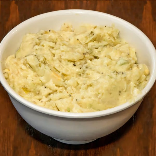 A white bowl filled with creamy potato salad, a classic BBQ side dish.
